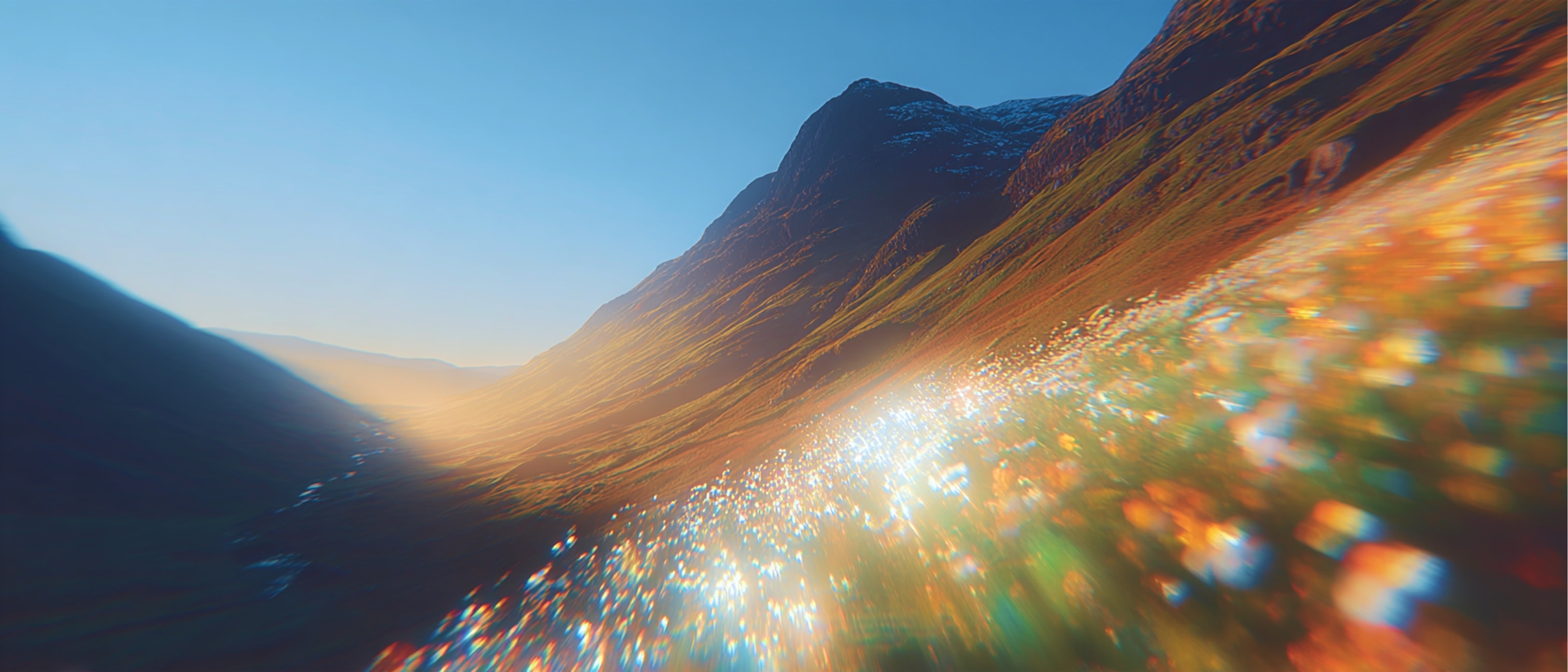 Sunlit mountain valley at golden hour with a layered field of spring wildflowers